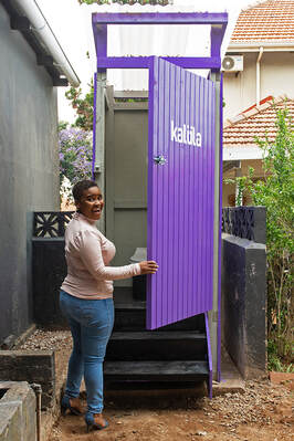 happy woman customer in durban in front of a kalula toilet